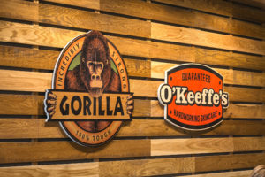 Wall made of wooden beam work displays Gorilla Glue and O'Keeffe's logos.