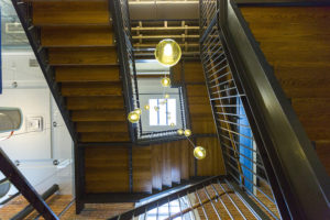 Upward view of large three-story staircase with light fixtures hanging down the center.
