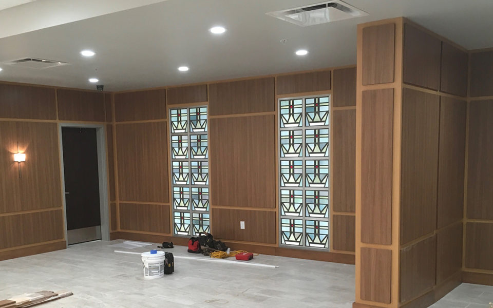 Corner of a lobby with custom wood paneling on the walls and stained glass windows.
