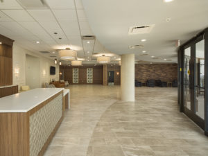 Large lobby of a church. Lots of natural light, neutral tones. Welcome desk to the left, seating areas in the back.