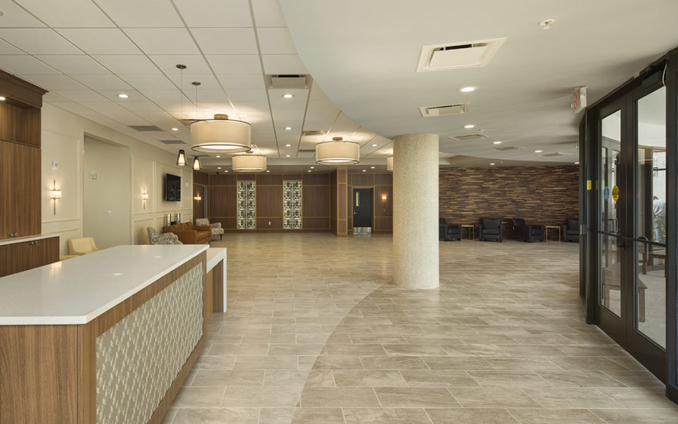 Large lobby of a church. Lots of natural light, neutral tones. Welcome desk to the left, seating areas in the back.